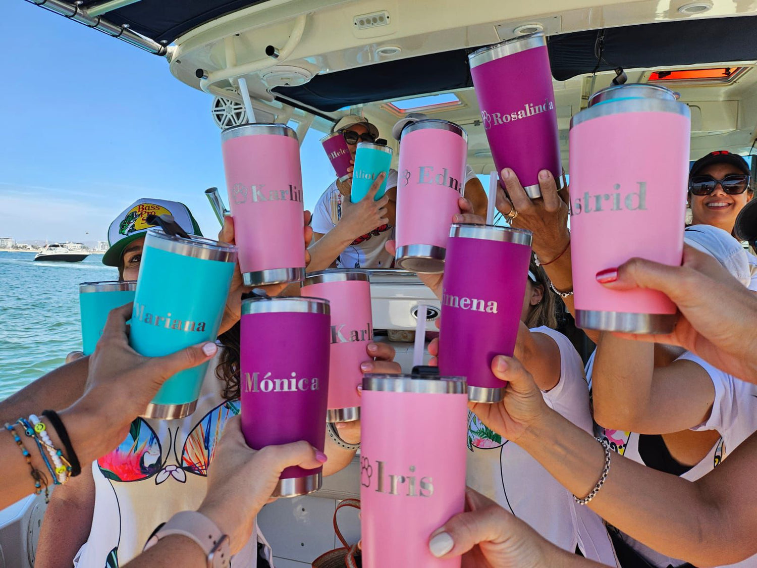 Foto real de termos Power 20oz de acero inoxidable con tapadera de acrílico, personalizados con nombres, en un ambiente de personas disfrutando en un yate.
